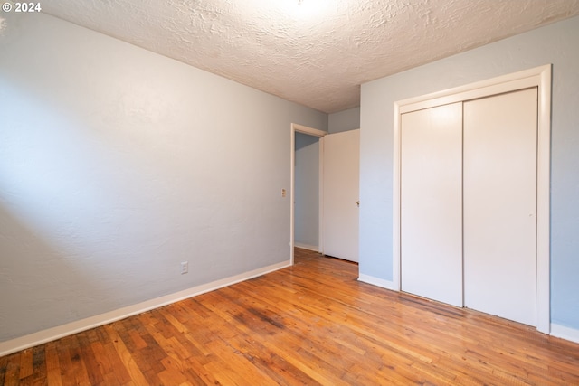 unfurnished bedroom featuring a closet, light hardwood / wood-style floors, and a textured ceiling