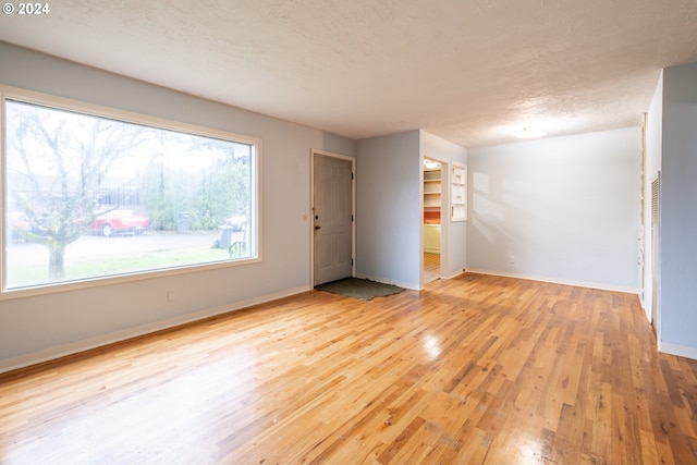 spare room featuring light hardwood / wood-style floors and a textured ceiling