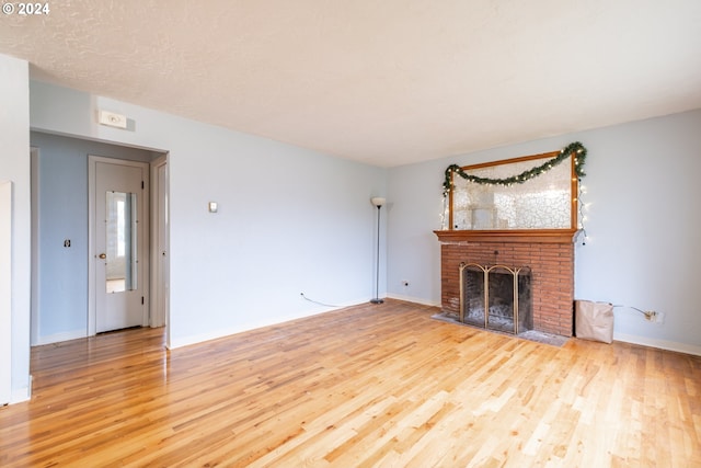 unfurnished living room featuring hardwood / wood-style flooring and a brick fireplace