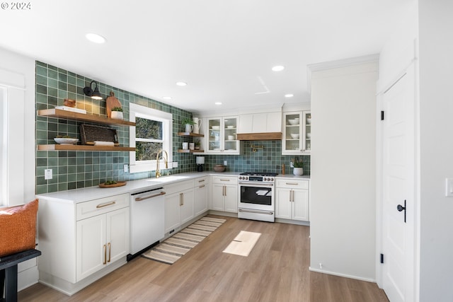 kitchen with light hardwood / wood-style floors, gas range oven, sink, white dishwasher, and white cabinetry