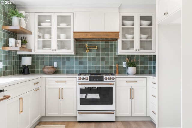 kitchen featuring tasteful backsplash, white cabinetry, light wood-type flooring, and white range with gas cooktop