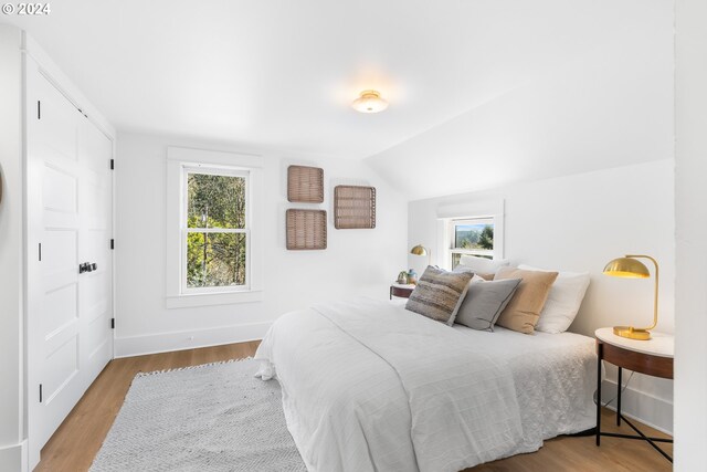 bedroom with vaulted ceiling and light hardwood / wood-style floors