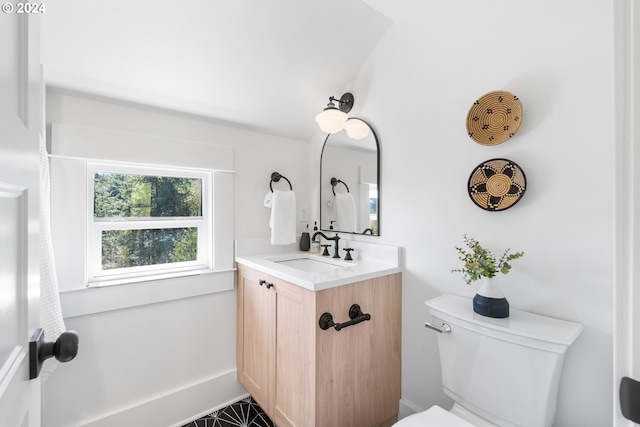 bathroom featuring toilet, vanity with extensive cabinet space, vaulted ceiling, and tile floors