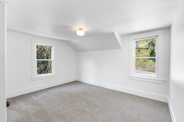 bonus room with light carpet, a healthy amount of sunlight, and lofted ceiling