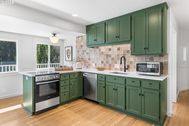 kitchen featuring backsplash, kitchen peninsula, light hardwood / wood-style flooring, and appliances with stainless steel finishes