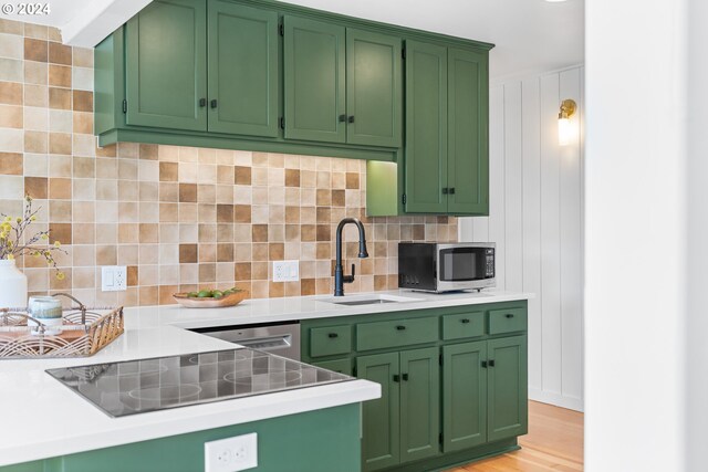 kitchen with green cabinets, appliances with stainless steel finishes, tasteful backsplash, and light wood-type flooring