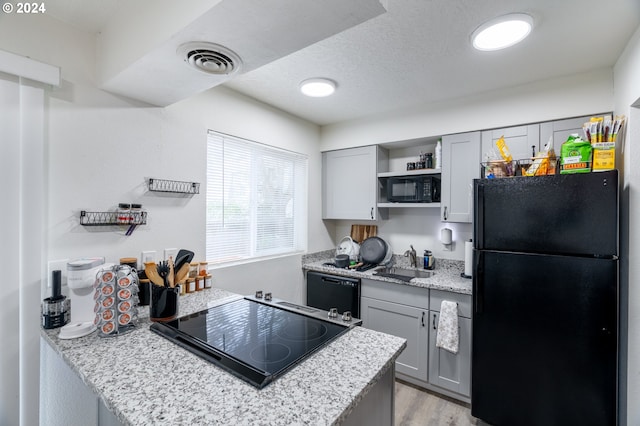 kitchen featuring light hardwood / wood-style floors, a textured ceiling, sink, black appliances, and gray cabinets