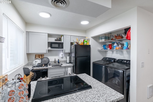 kitchen with gray cabinetry, light stone countertops, sink, washer and clothes dryer, and black appliances