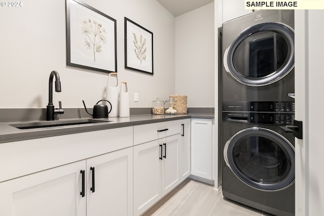 laundry room featuring cabinets, stacked washing maching and dryer, and sink