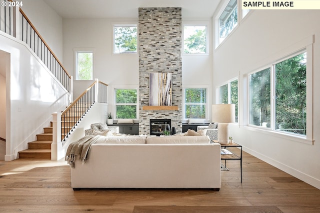 living room with a fireplace, light hardwood / wood-style floors, and a high ceiling