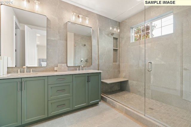 bathroom with tile patterned floors, vanity, a shower with shower door, and tile walls