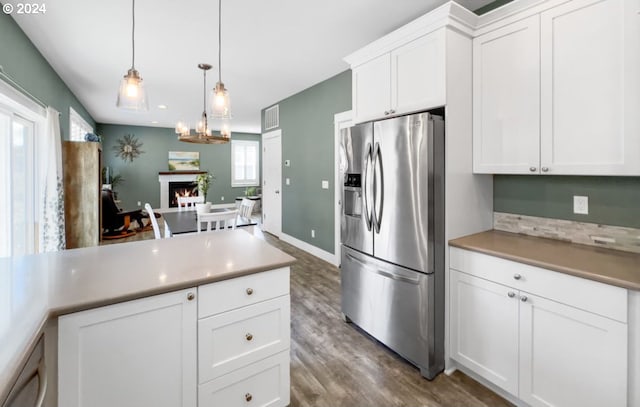 kitchen featuring white cabinets, stainless steel refrigerator with ice dispenser, decorative light fixtures, and a wealth of natural light