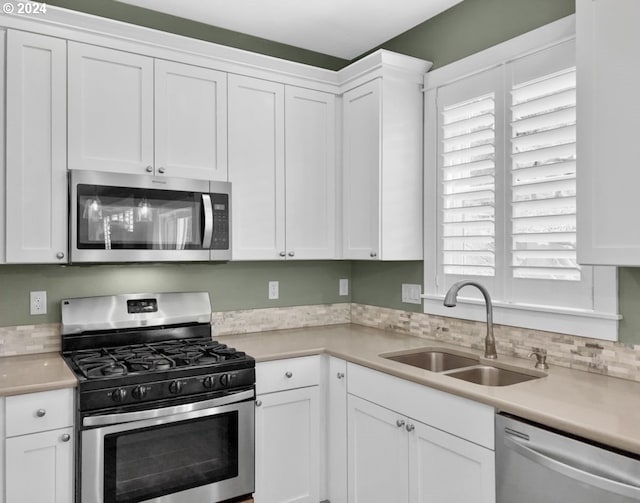 kitchen featuring stainless steel appliances, sink, a healthy amount of sunlight, and white cabinetry