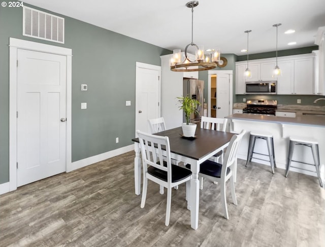 dining room with sink, a chandelier, and light hardwood / wood-style flooring