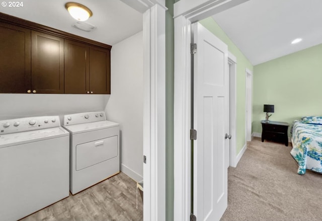 clothes washing area with light carpet, washing machine and clothes dryer, and cabinets