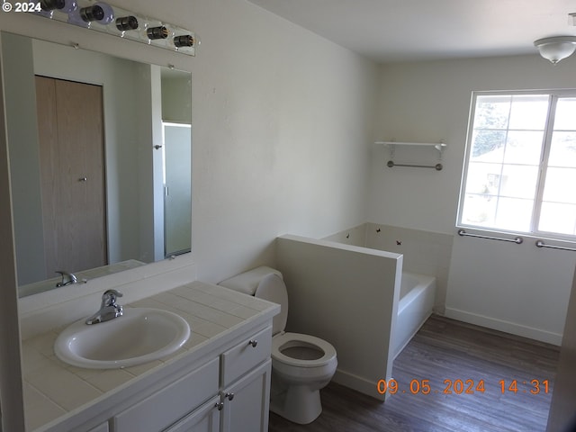 bathroom featuring vanity, hardwood / wood-style flooring, toilet, and a bath