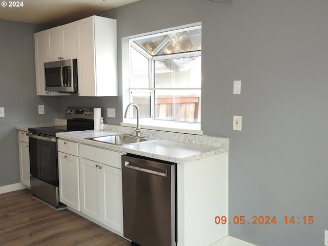 kitchen featuring appliances with stainless steel finishes, sink, dark hardwood / wood-style flooring, and white cabinetry