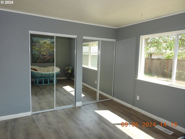 unfurnished bedroom with hardwood / wood-style flooring and ornamental molding