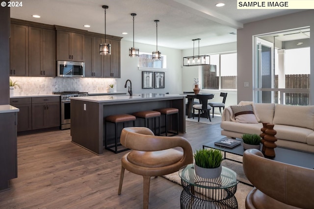 kitchen featuring tasteful backsplash, a breakfast bar area, appliances with stainless steel finishes, open floor plan, and light countertops