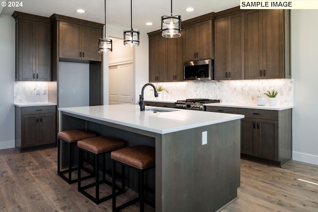 kitchen featuring wood finished floors, stainless steel microwave, a sink, and range