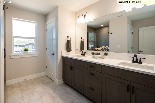 bathroom featuring baseboards, double vanity, a sink, and a shower stall