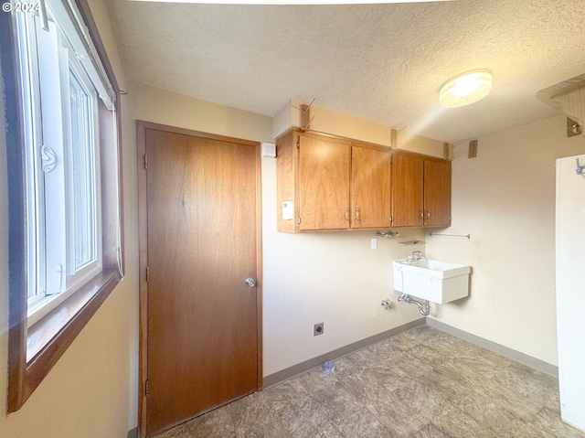 laundry room with sink, electric dryer hookup, cabinets, and a textured ceiling