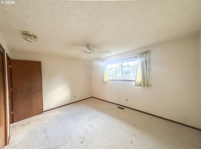 unfurnished bedroom featuring ceiling fan, light colored carpet, a textured ceiling, and a closet