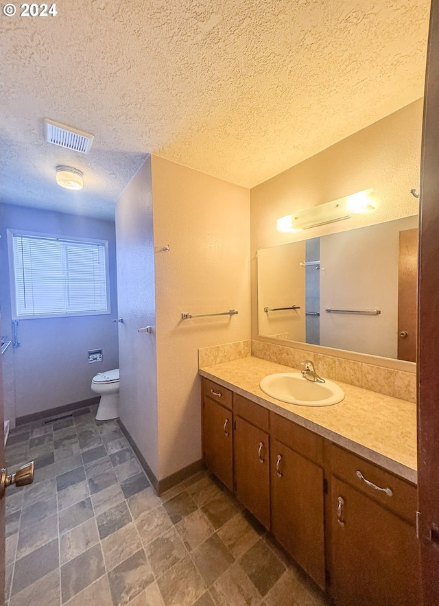 bathroom with vanity, a textured ceiling, and toilet