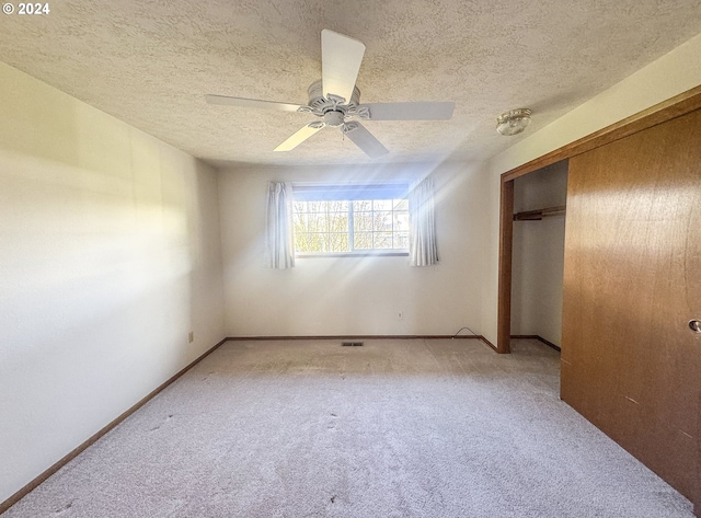 unfurnished bedroom with ceiling fan, a closet, light carpet, and a textured ceiling