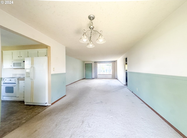 carpeted spare room with a chandelier