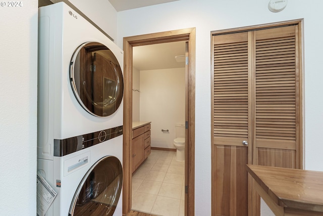 washroom with stacked washing maching and dryer and light tile patterned floors