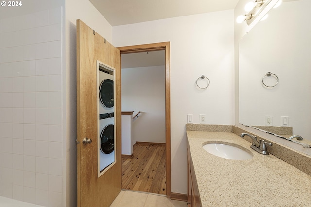 bathroom with vanity, stacked washer and clothes dryer, and hardwood / wood-style flooring