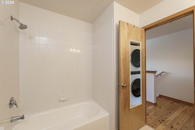 bathroom with tiled shower / bath, wood-type flooring, and stacked washer / dryer