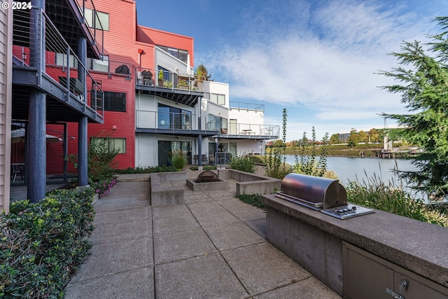 view of patio featuring a water view, exterior kitchen, and grilling area