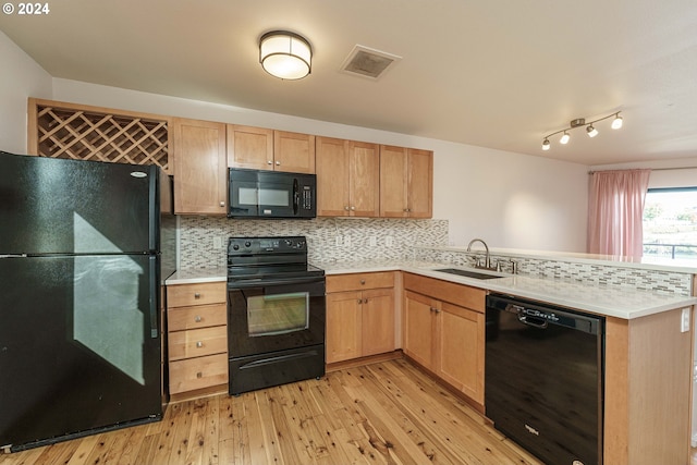 kitchen featuring kitchen peninsula, sink, light hardwood / wood-style flooring, and black appliances