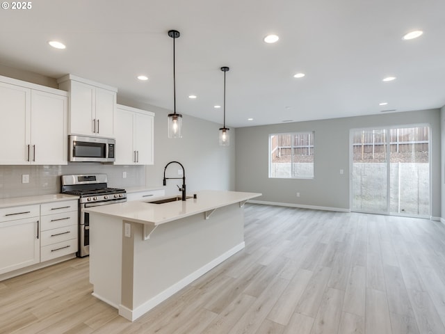 724 NW 178th Way, Ridgefield, WA 98642 - kitchen featuring stainless steel appliances, a sink, light wood-type flooring, baseboards, and decorative backsplash