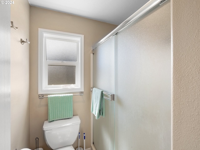 bathroom with toilet and a shower with shower door