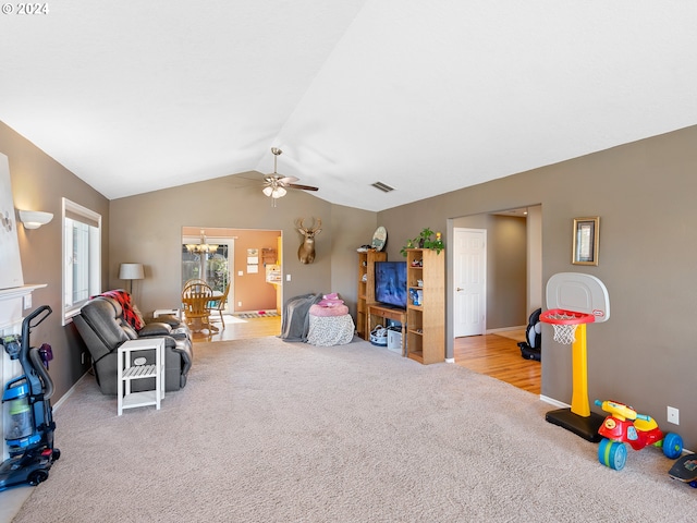 recreation room featuring ceiling fan with notable chandelier, light colored carpet, and lofted ceiling