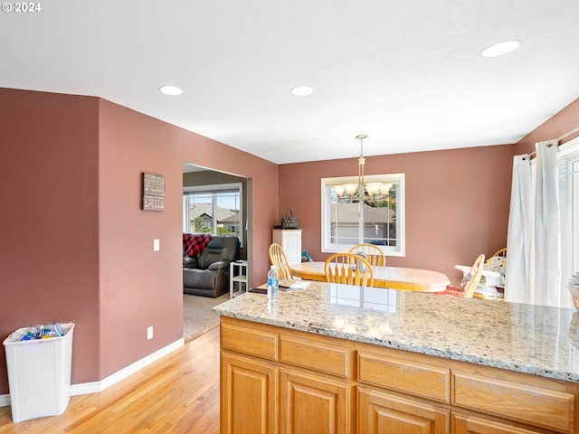 kitchen with pendant lighting, plenty of natural light, light stone counters, and light wood-type flooring