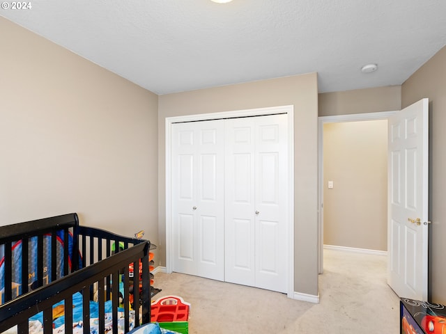 bedroom with a closet, light carpet, and a nursery area