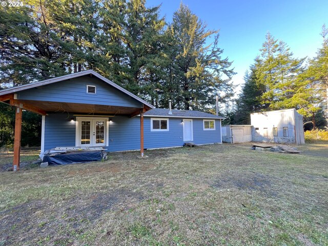 rear view of property with french doors and a yard