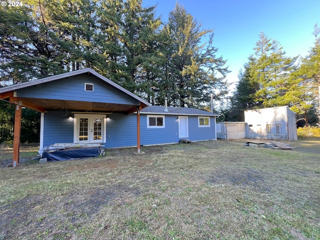 back of property with french doors and a lawn