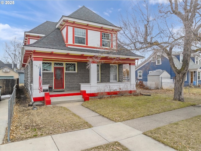 view of front of home featuring a porch, fence, a front lawn, and roof with shingles