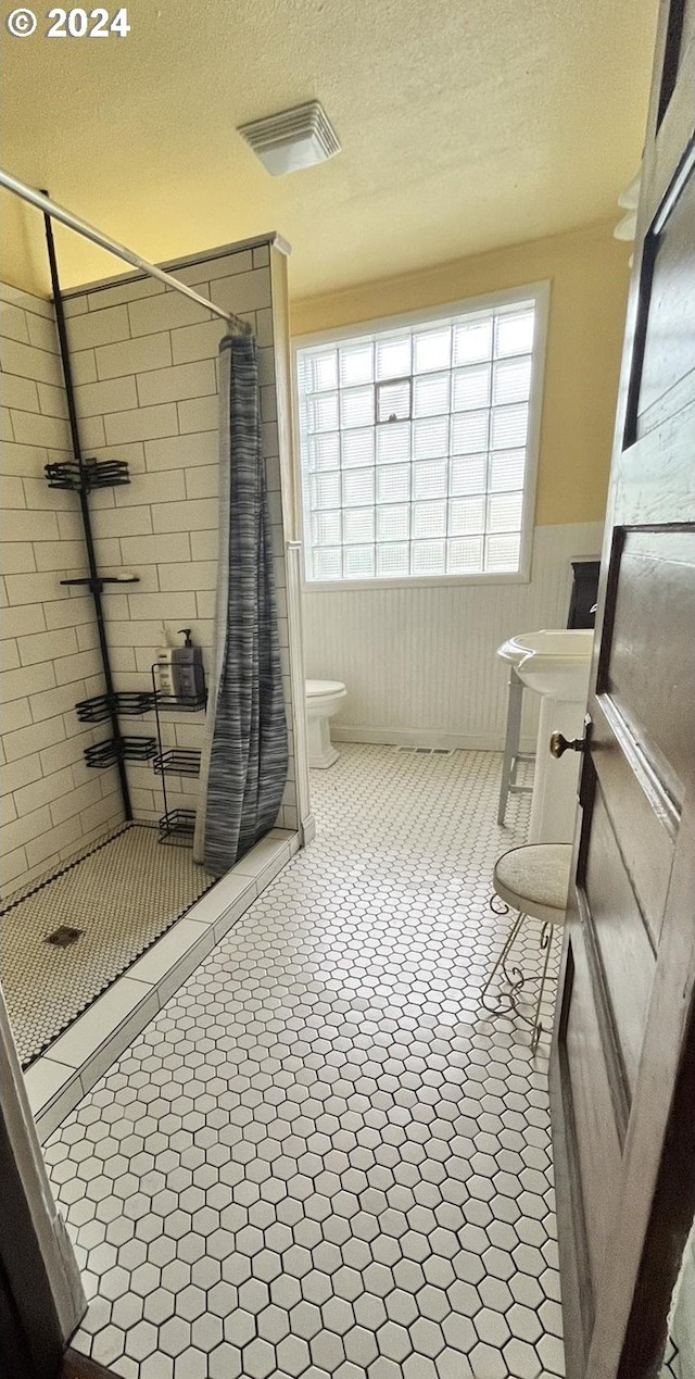 bathroom featuring a shower with curtain, a textured ceiling, and toilet