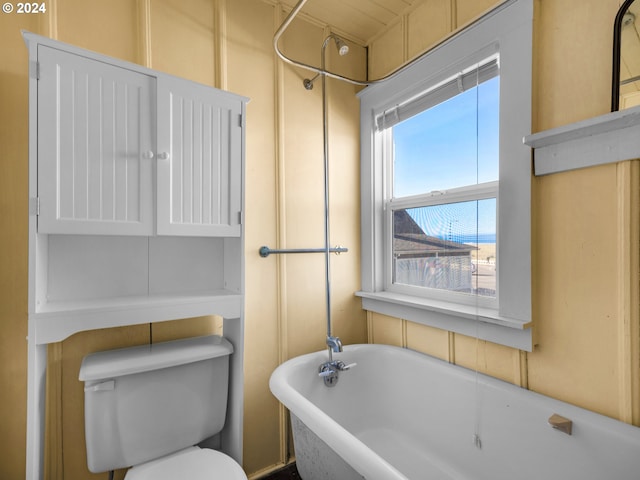 bathroom featuring a bath, toilet, and a wealth of natural light