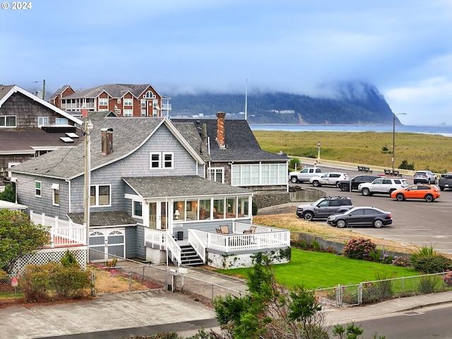 back of property featuring a deck with water view and a yard