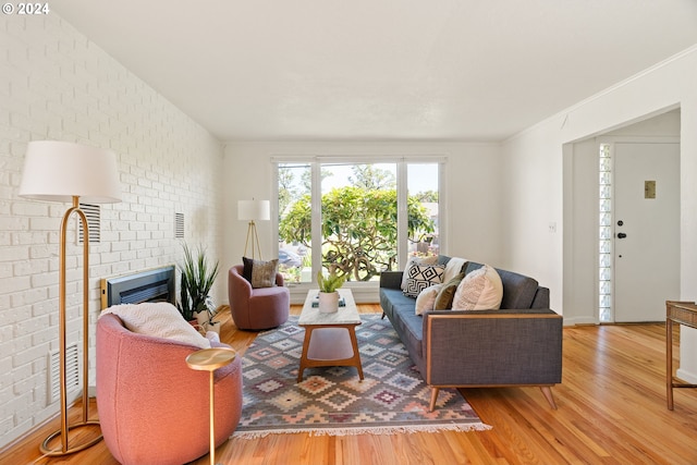 living room featuring a brick fireplace, brick wall, and hardwood / wood-style floors