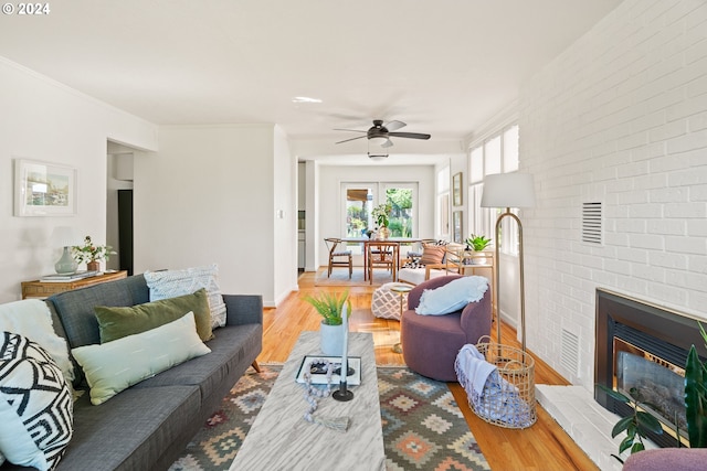 living room featuring a fireplace, light hardwood / wood-style flooring, ceiling fan, and crown molding