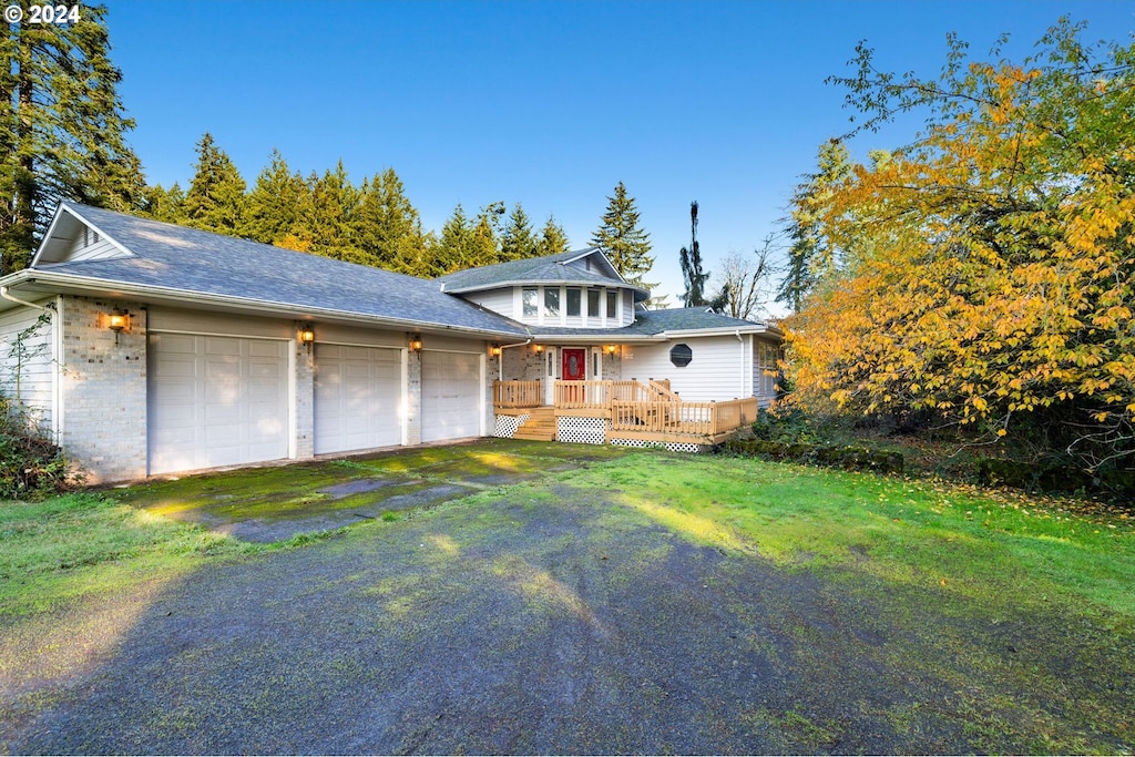 view of front facade featuring a deck, a garage, and a front yard