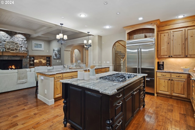 kitchen with a fireplace, stainless steel appliances, a center island, and light wood-type flooring